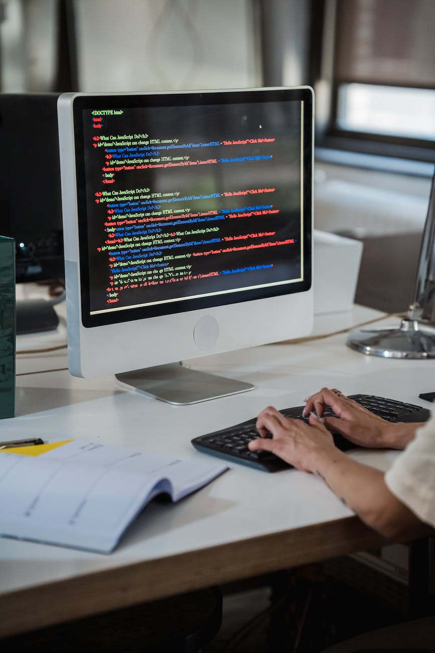 vertical shot of woman writing on computer in an office and colour code on a computer screen